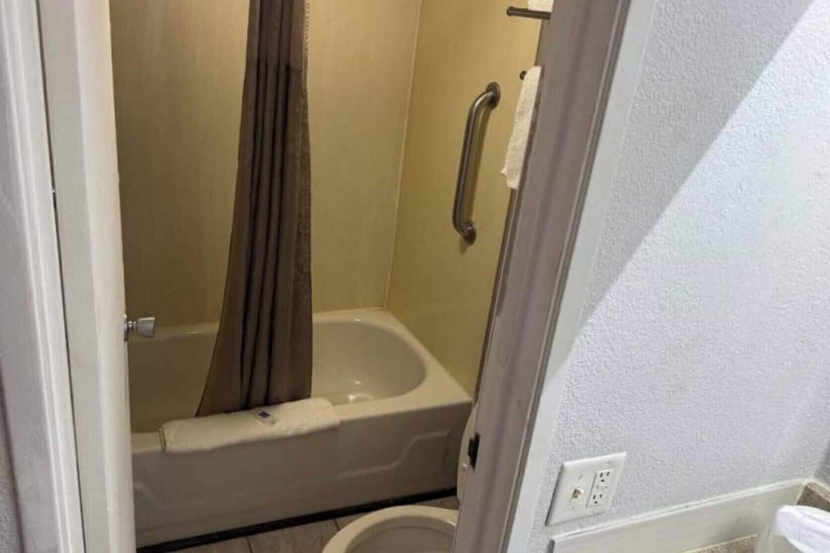 A small, enclosed bathroom with a bathtub, a shower curtain, and a toilet.