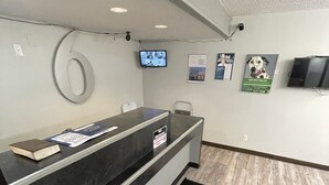 Un área de recepción con un mostrador negro, un televisor montado en la pared y un cartel con un perro dálmata.