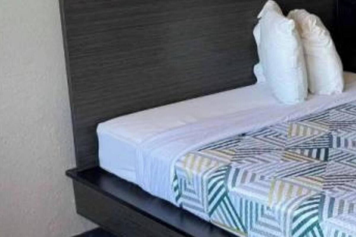 A modern bed with a dark headboard, white pillows, and a patterned bedspread.