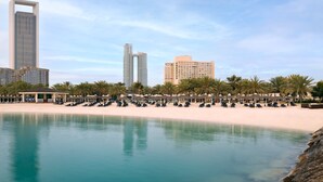 A beachfront hotel with a pool, beach chairs, and palm trees. - InterContinental Abu Dhabi by IHG (Abu Dhabi)