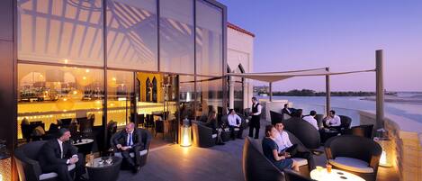 Un bar en la azotea con mesas al aire libre y vistas al mar.
