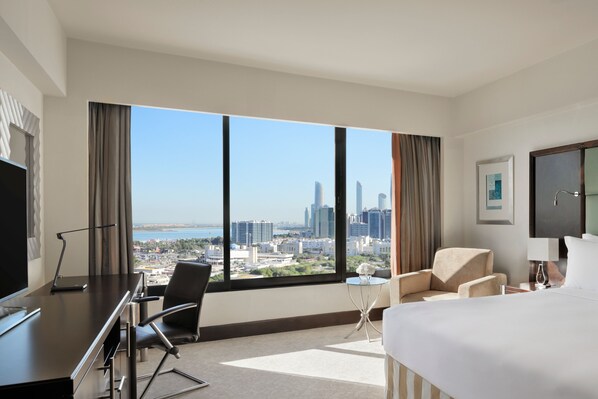A hotel room with a large window, a bed, a desk, a chair, and a TV. - InterContinental Abu Dhabi by IHG (Abu Dhabi)