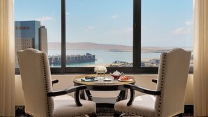A room with two chairs facing a large window with a view of a body of water and distant land. - InterContinental Abu Dhabi by IHG (Abu Dhabi)