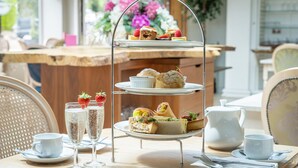 A three-tiered dessert stand with various pastries and sandwiches, accompanied by cups of tea and glasses of champagne. - Waterton Park Hotel (Wakefield)