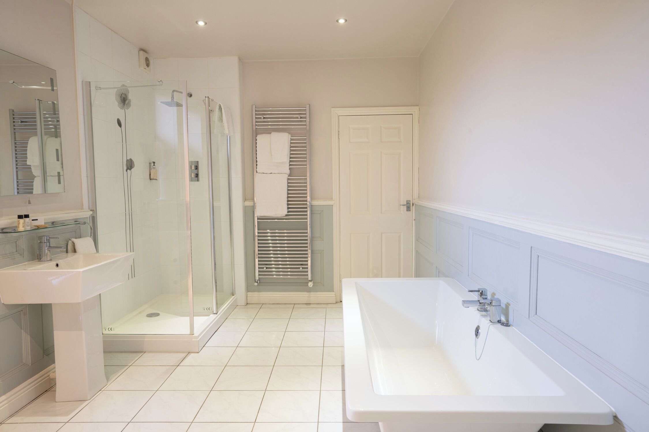 A modern bathroom with a glass-enclosed shower, a large bathtub, and a sink.