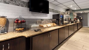 Una cocina moderna con televisor de pantalla plana, una zona de café y una exhibición de frutas.