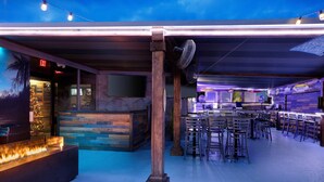 Zona de bar con chimenea, detalles de madera y disposición de asientos.