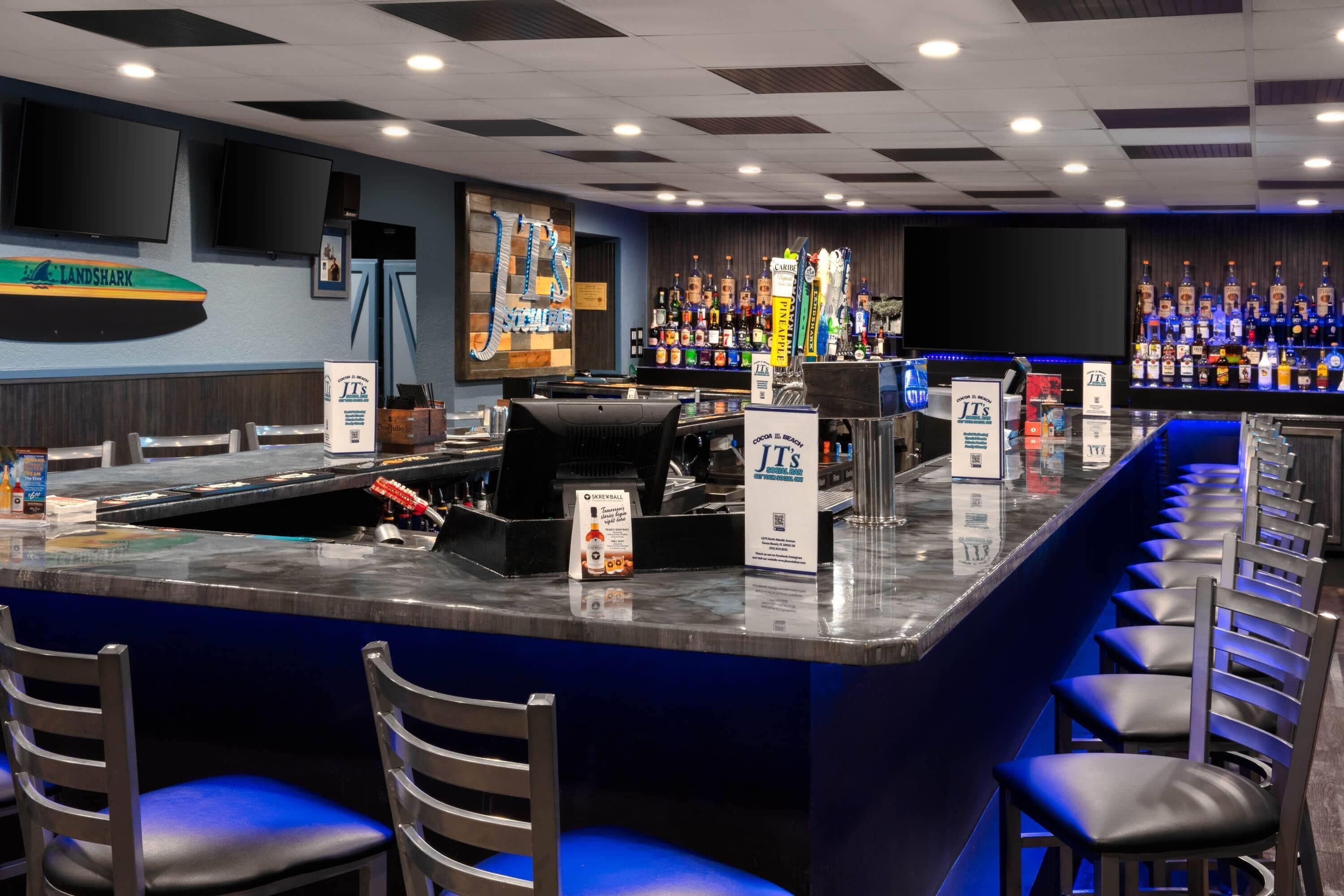 A bar area with a counter, stools, and a variety of liquor bottles.