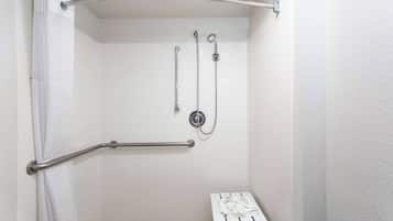 A shower with a grab bar, a handheld showerhead, and a wall-mounted faucet.