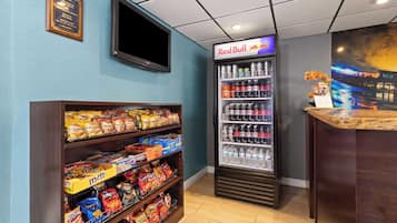 Un bar de aperitivos con estantes llenos de papas fritas y un refrigerador para bebidas.