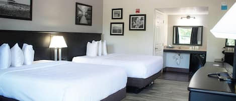Habitación de hotel con dos camas, un escritorio, un espejo y una lámpara.