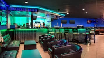 Zona de bar con asientos de cuero, una barra con botellas y una pared azul.