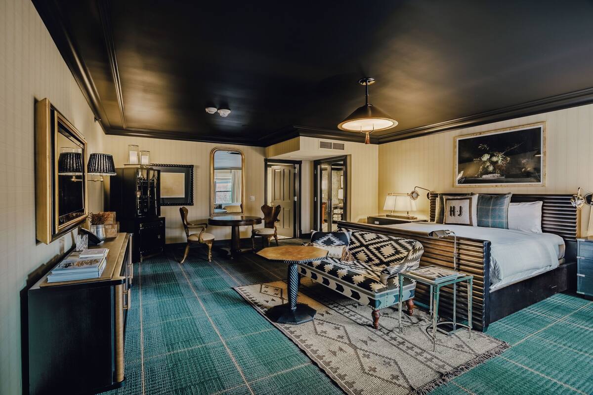Une chambre d’hôtel avec un lit, un canapé, un bureau et une chaise. Il y a une fenêtre et une porte.