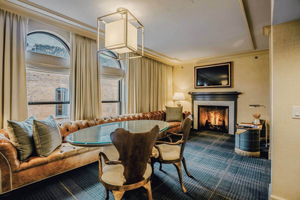 Un salon chaleureux avec un canapé en cuir, une table basse en verre et une cheminée.