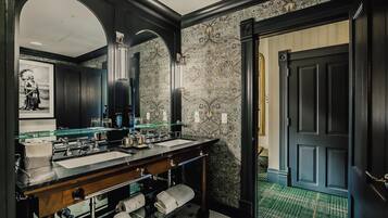 A luxurious bathroom with a double sink vanity, a large mirror, and a decorative wall.