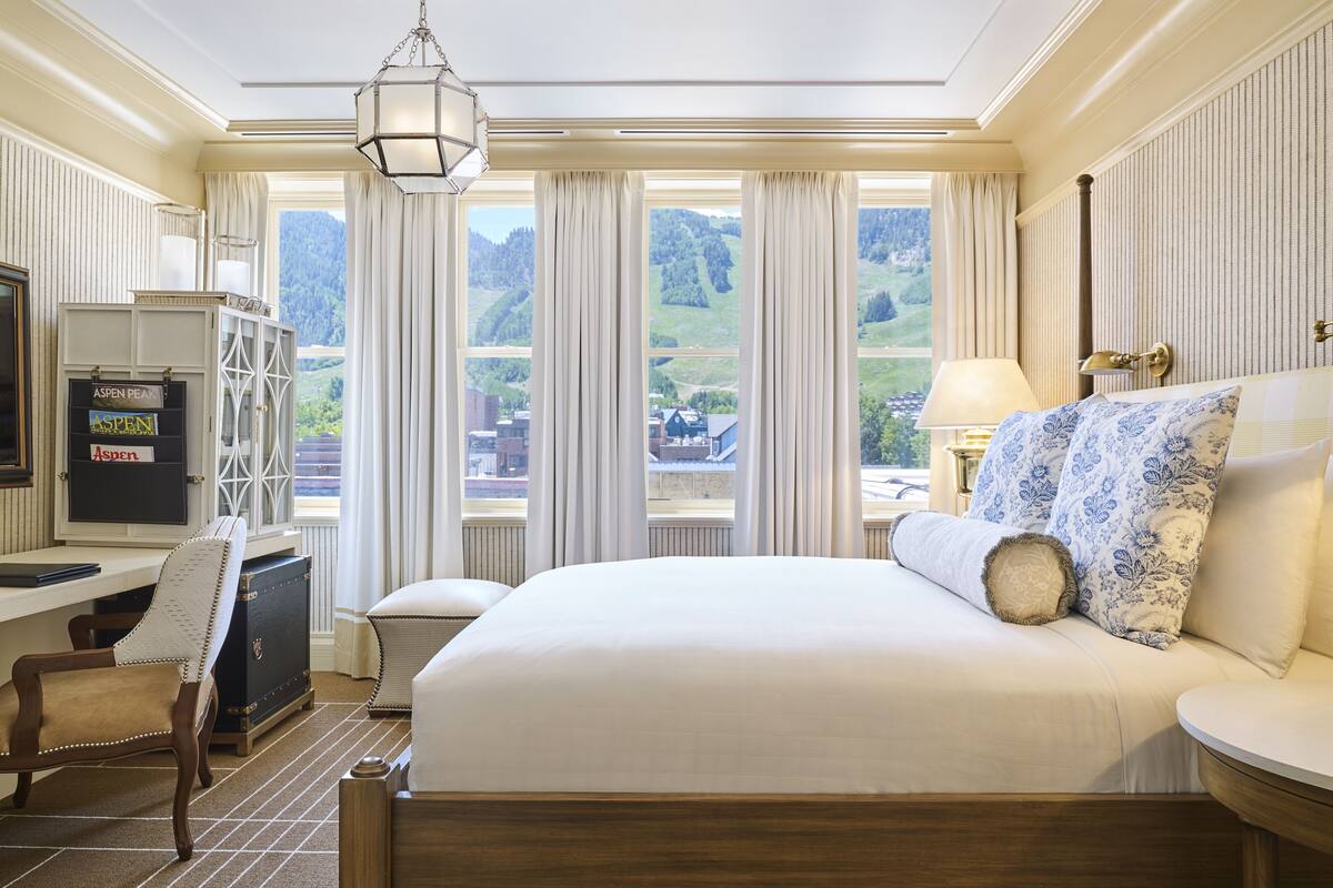 Une chambre d’hôtel avec un grand lit, un bureau et une vue sur les montagnes.