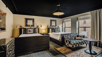 A modern hotel room with a large bed, a sofa, a small table, and a window with curtains.