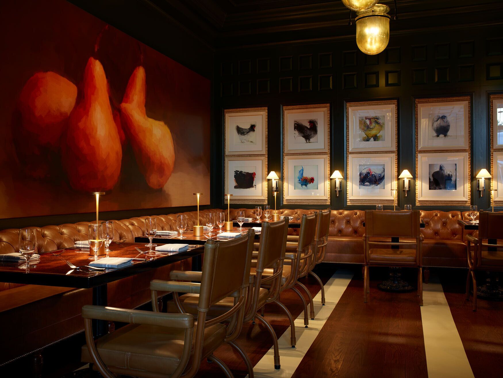 A restaurant with leather booths, framed artwork on the walls, and a large painting of fruits.