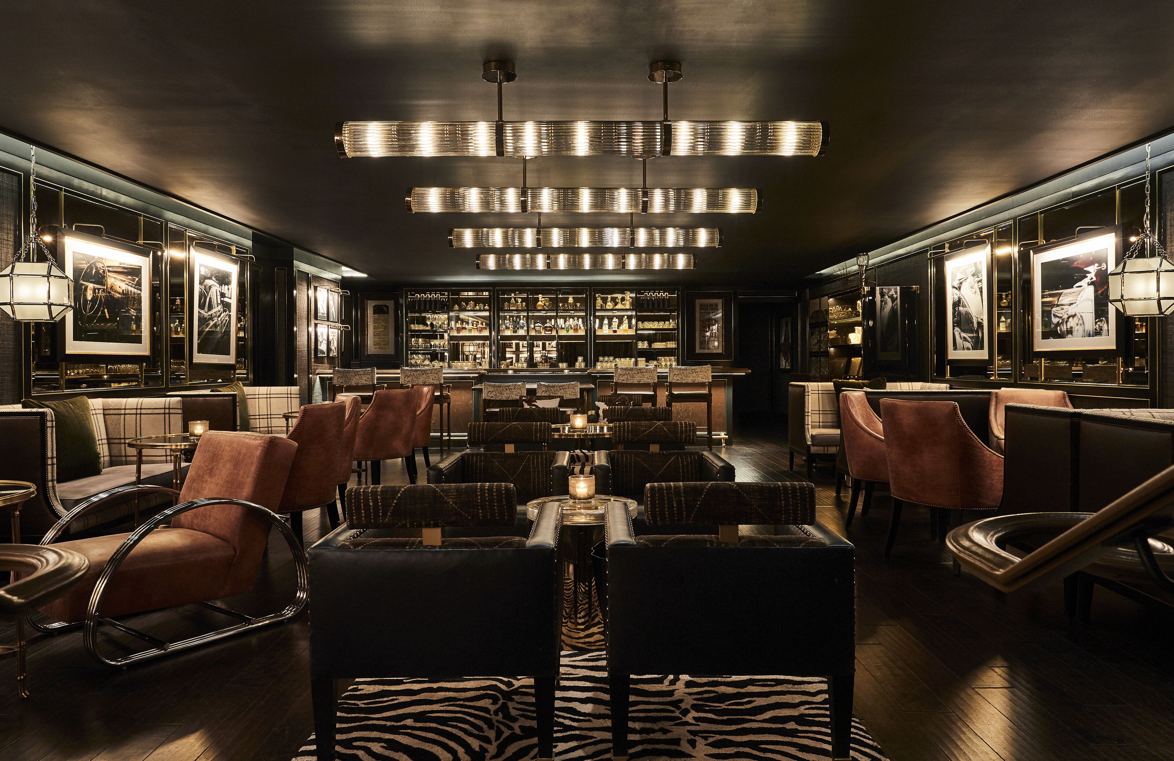 A bar area with seating, a zebra-patterned rug, and framed pictures on the walls.
