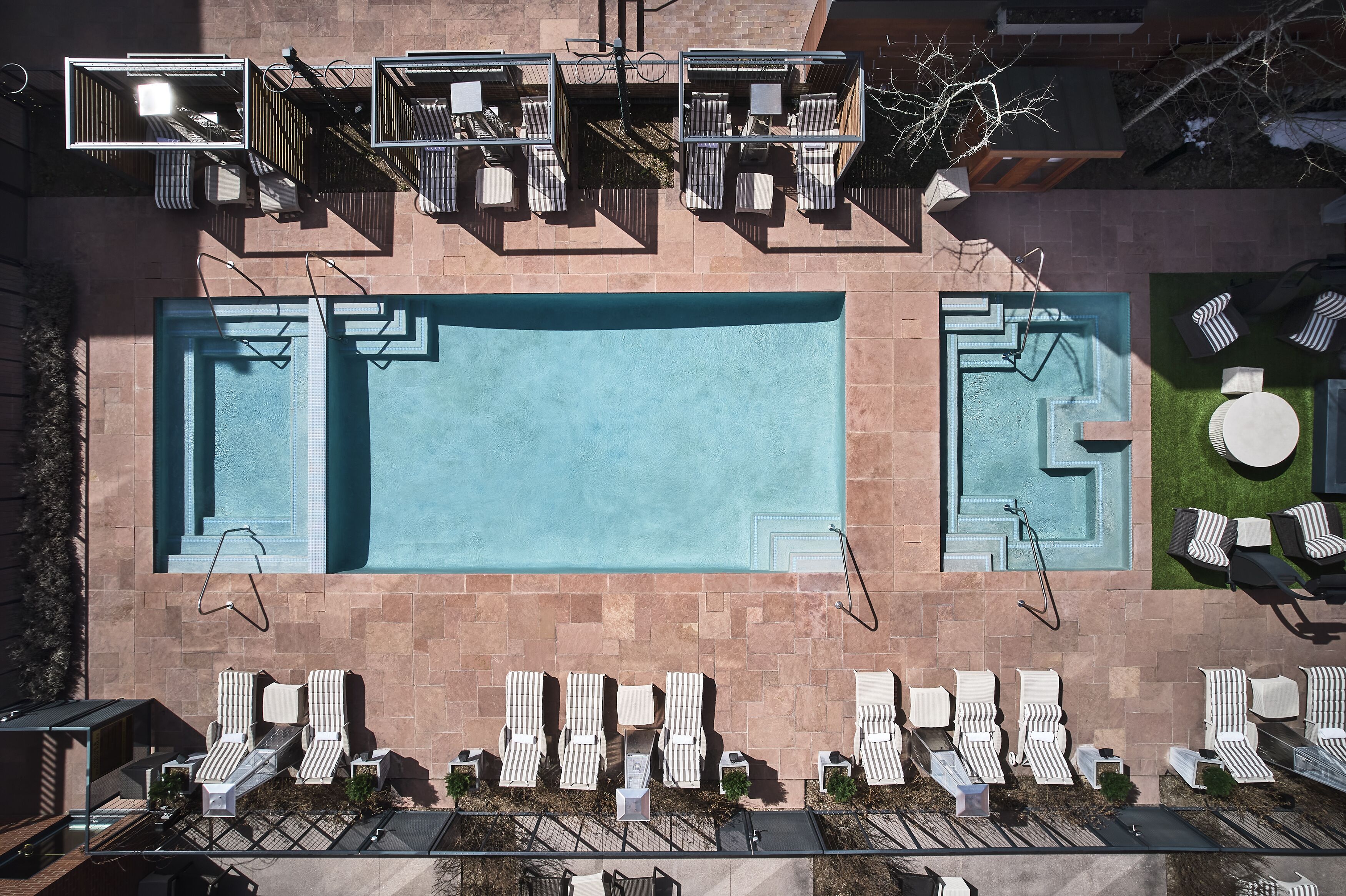 An aerial view of a rooftop pool area with multiple lounge chairs and a large swimming pool.