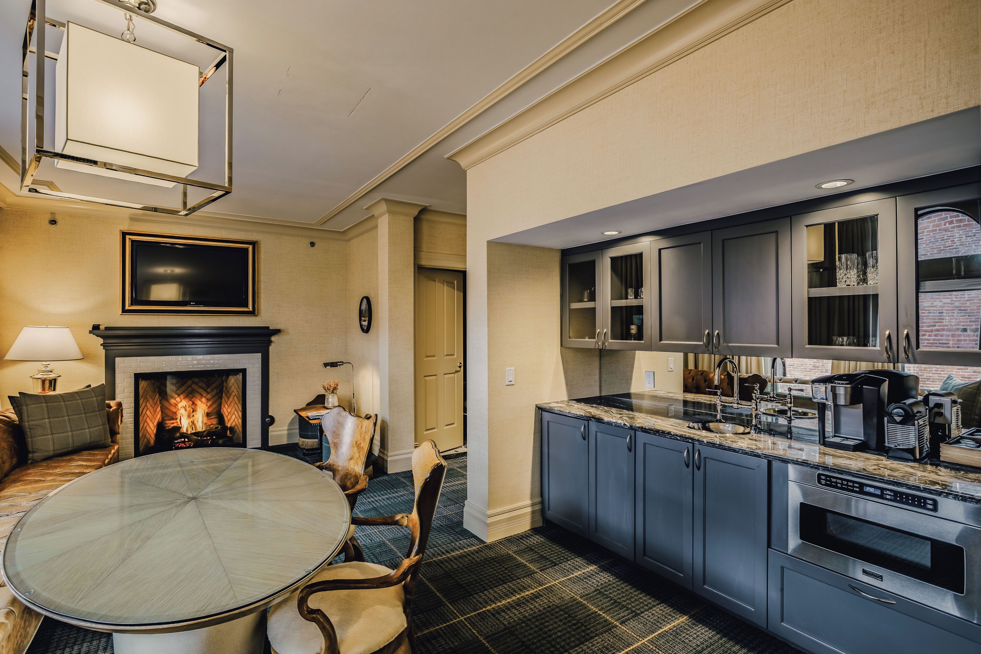 A modern kitchen with stainless steel appliances, a dining area with a glass table, and a fireplace.