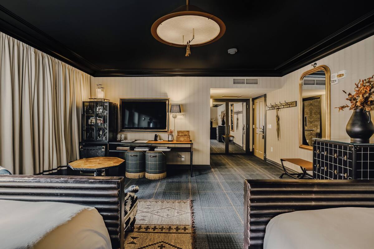 Une chambre d’hôtel avec un grand lit, un canapé, un bureau avec une lampe, une télévision et un miroir.