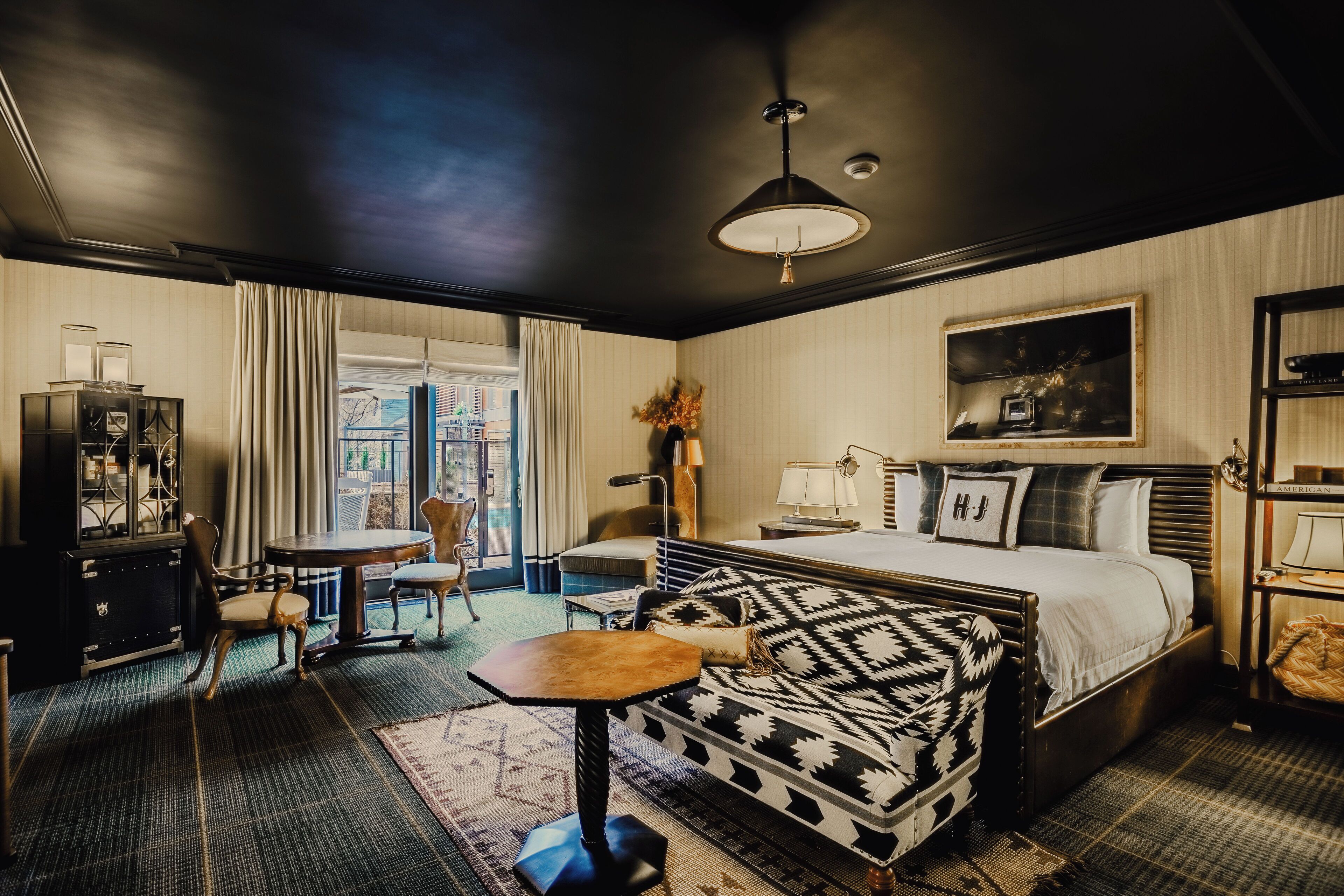 Et hotelværelse med seng, sofa, lille bord, stol, skrivebord og skab.