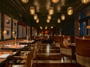 A dimly lit restaurant with wooden furniture and hanging lamps.