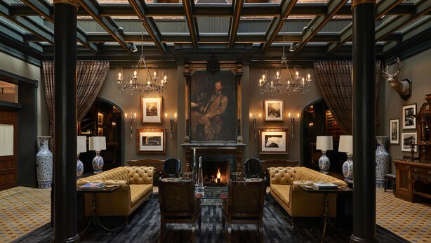 A grand room with a fireplace, two sofas, and a large painting on the wall.