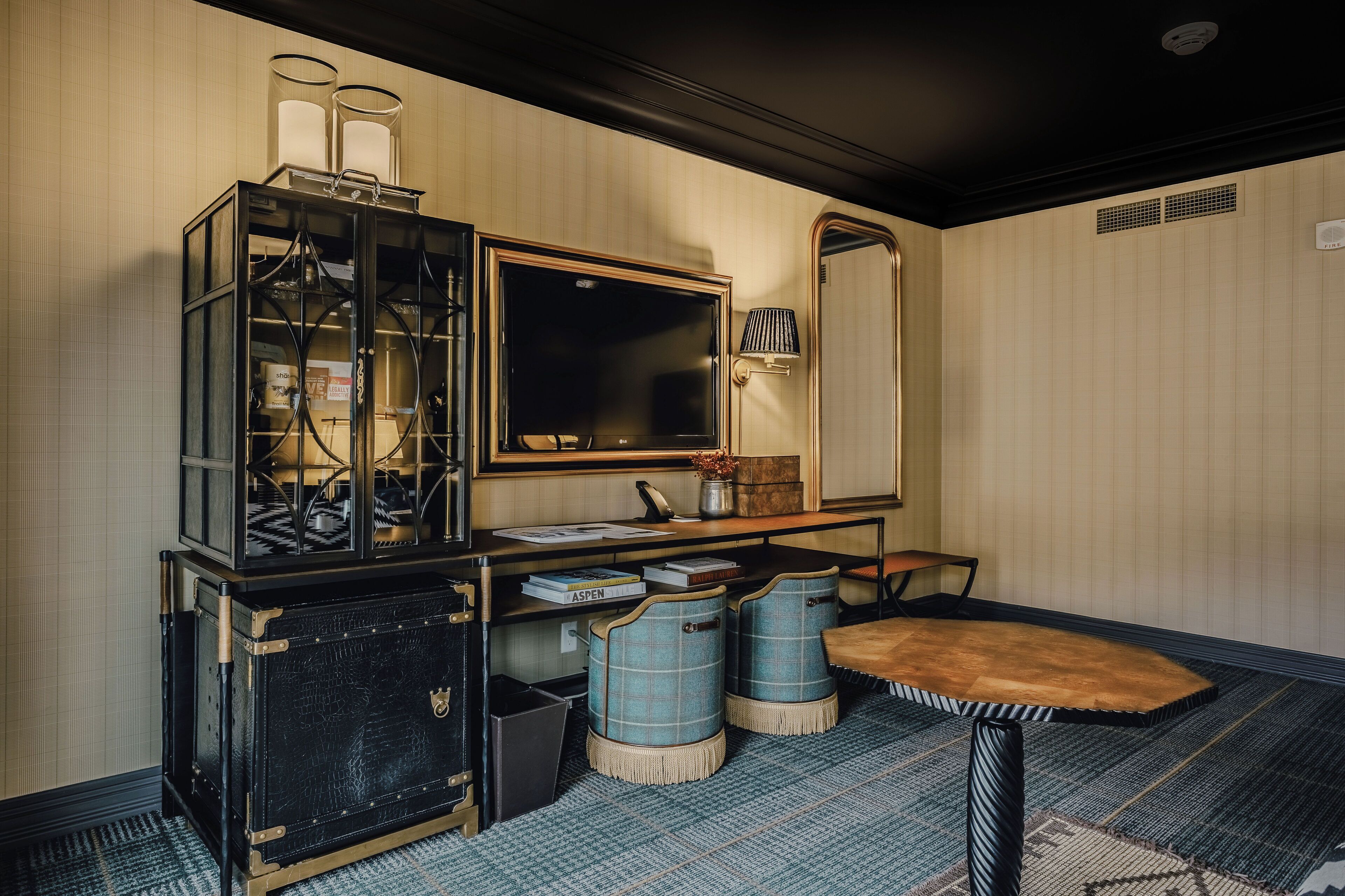 A room with a vintage desk, a mirror, and a small table.