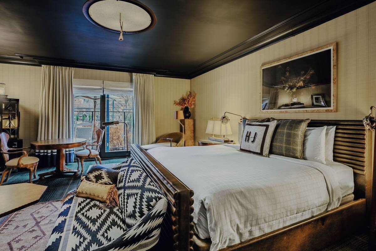 Une chambre d’hôtel avec un grand lit, une table ronde, une chaise et une vue sur l’extérieur.