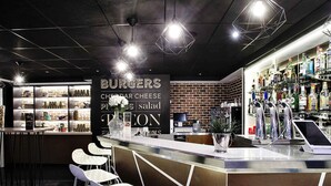 A bar area with stools, a counter, and a menu board. - Novotel Toulouse Purpan Aéroport (Toulouse)