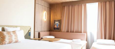 A hotel room with a large bed, a smaller bed, a sofa, and a table.