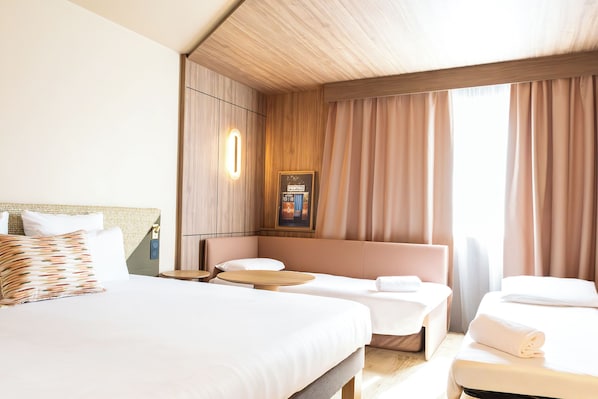 A hotel room with a large bed, a smaller bed, a sofa, and a table.