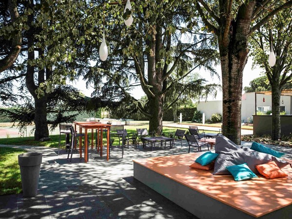Un espacio al aire libre con mesas y sillas, rodeado de árboles.