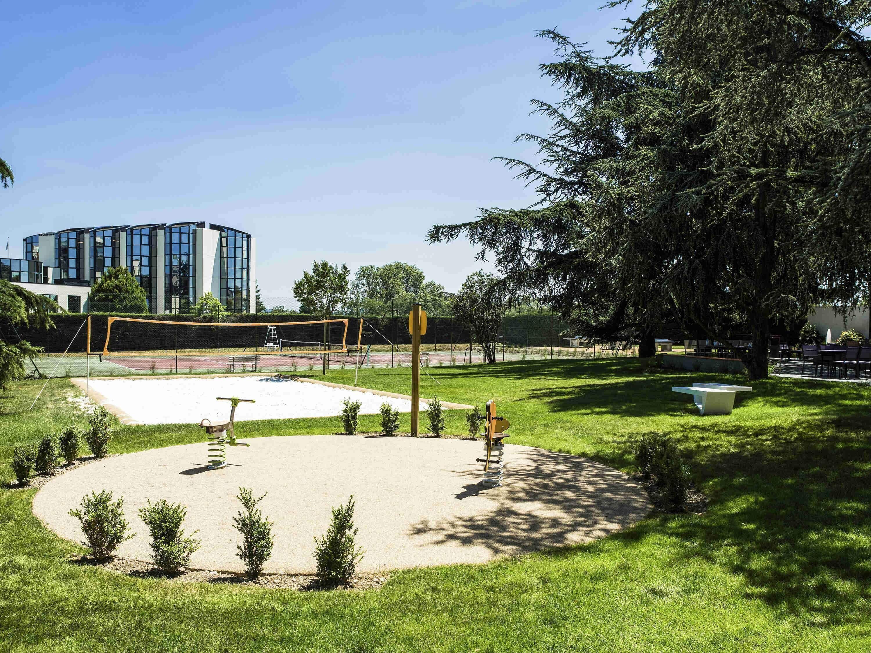Un parc équipé d’un filet de volley-ball, d’une balançoire et d’un banc.