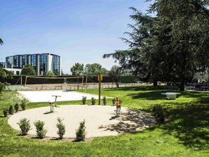 Un parque con una red de voleibol, un columpio y un banco.