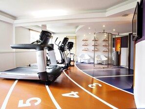 Una palestra con tapis roulant, cyclette e vogatore.