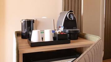A hotel room's minibar with a coffee maker, a water dispenser, and a tray with cups and condiments.