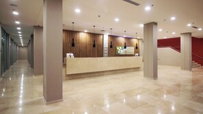 Una moderna zona de recepción con piso de mármol, paneles de madera y mostrador de recepción.