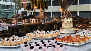 Diversas sobremesas em uma mesa de buffet, incluindo bolos e doces com frutas.