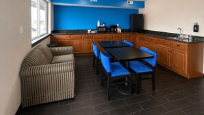 A compact kitchen with a dining area, featuring a sofa, two tables with chairs, and a refrigerator. - Rodeway Inn (Vernal)