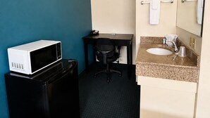 A hotel room with a bed, a desk with a chair, a microwave, a sink, and a mirror. - Rodeway Inn (Vernal)