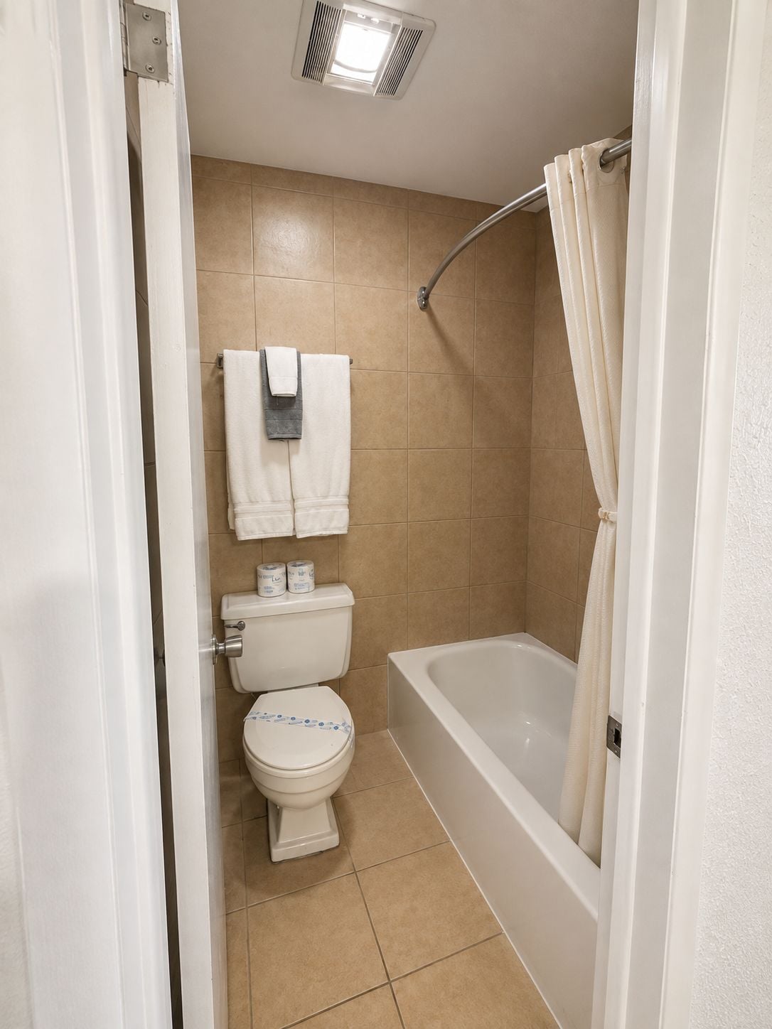 Une salle de bain équipée de toilettes, d’une baignoire et d’un rideau de douche.