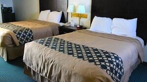 A hotel room with two beds, each with a headboard, a nightstand with a lamp, and a small table with a telephone. - Rodeway Inn (Vernal)