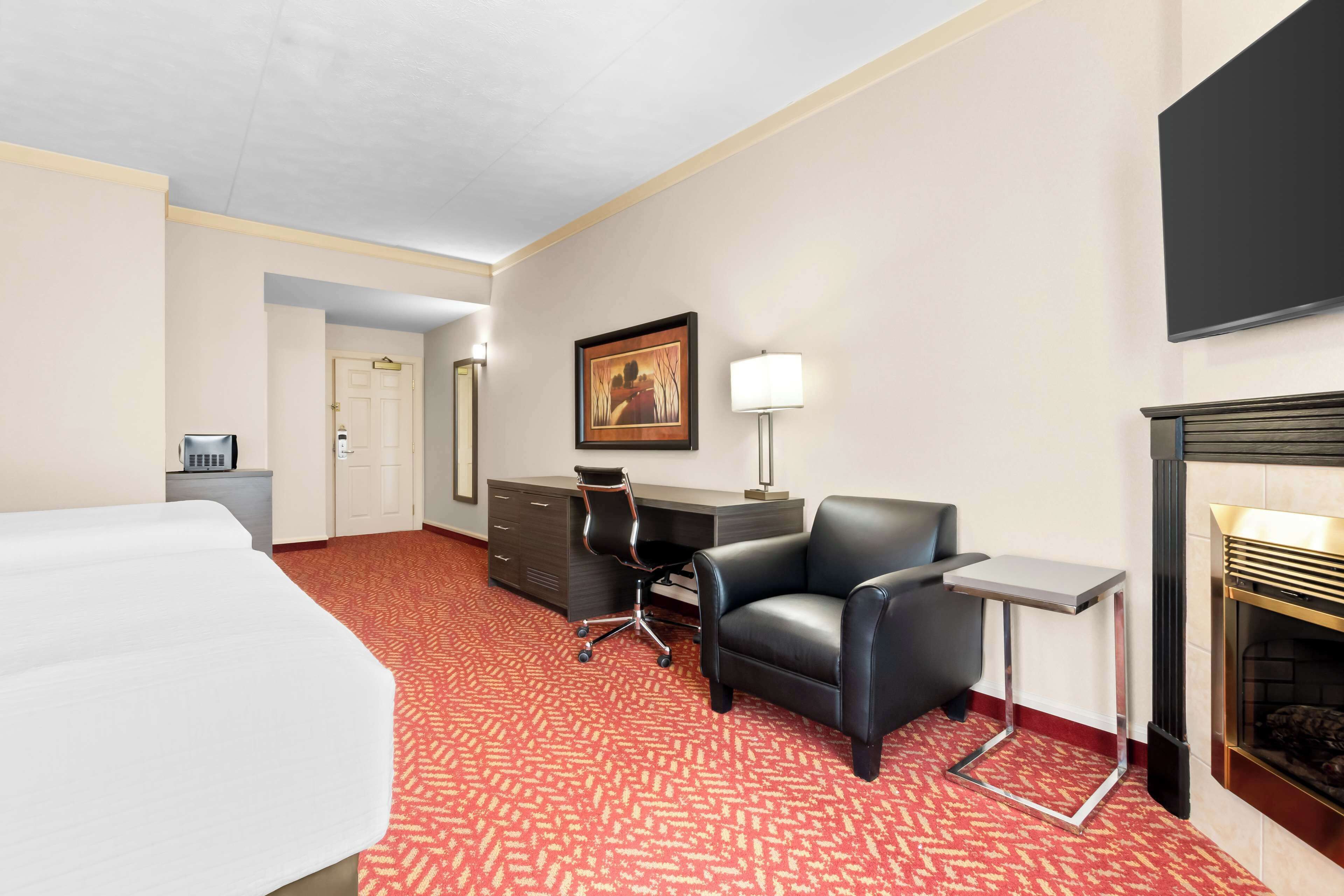 Une chambre d’hôtel équipée d’un lit, d’un bureau, d’un fauteuil de bureau et d’une cheminée.