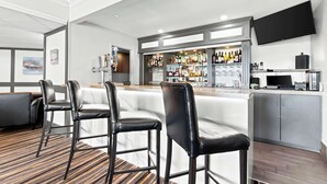 Een bar met een toonbank, barstoelen en een televisie aan de muur.