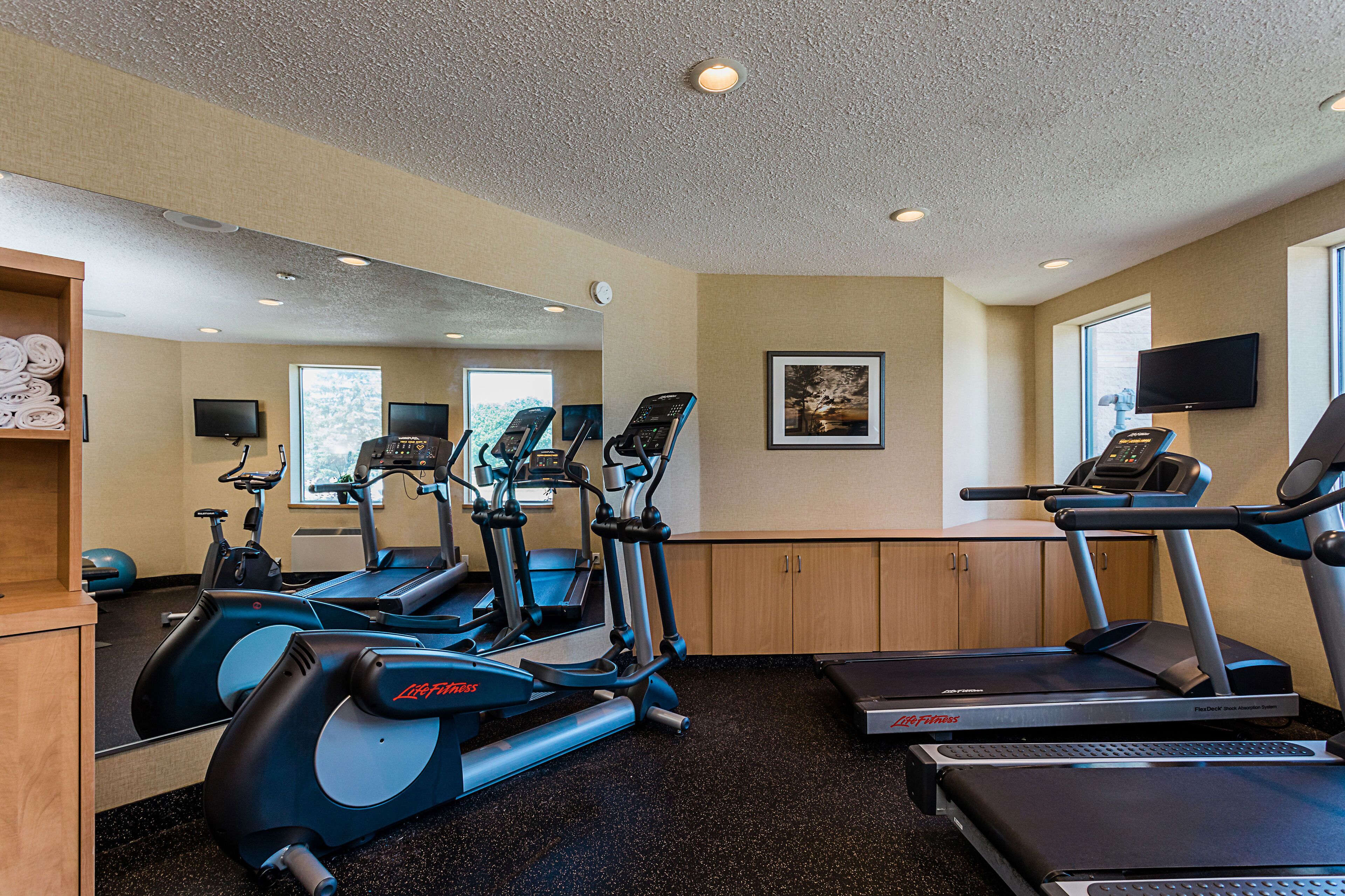 A gym with treadmills, elliptical machines, and exercise balls.