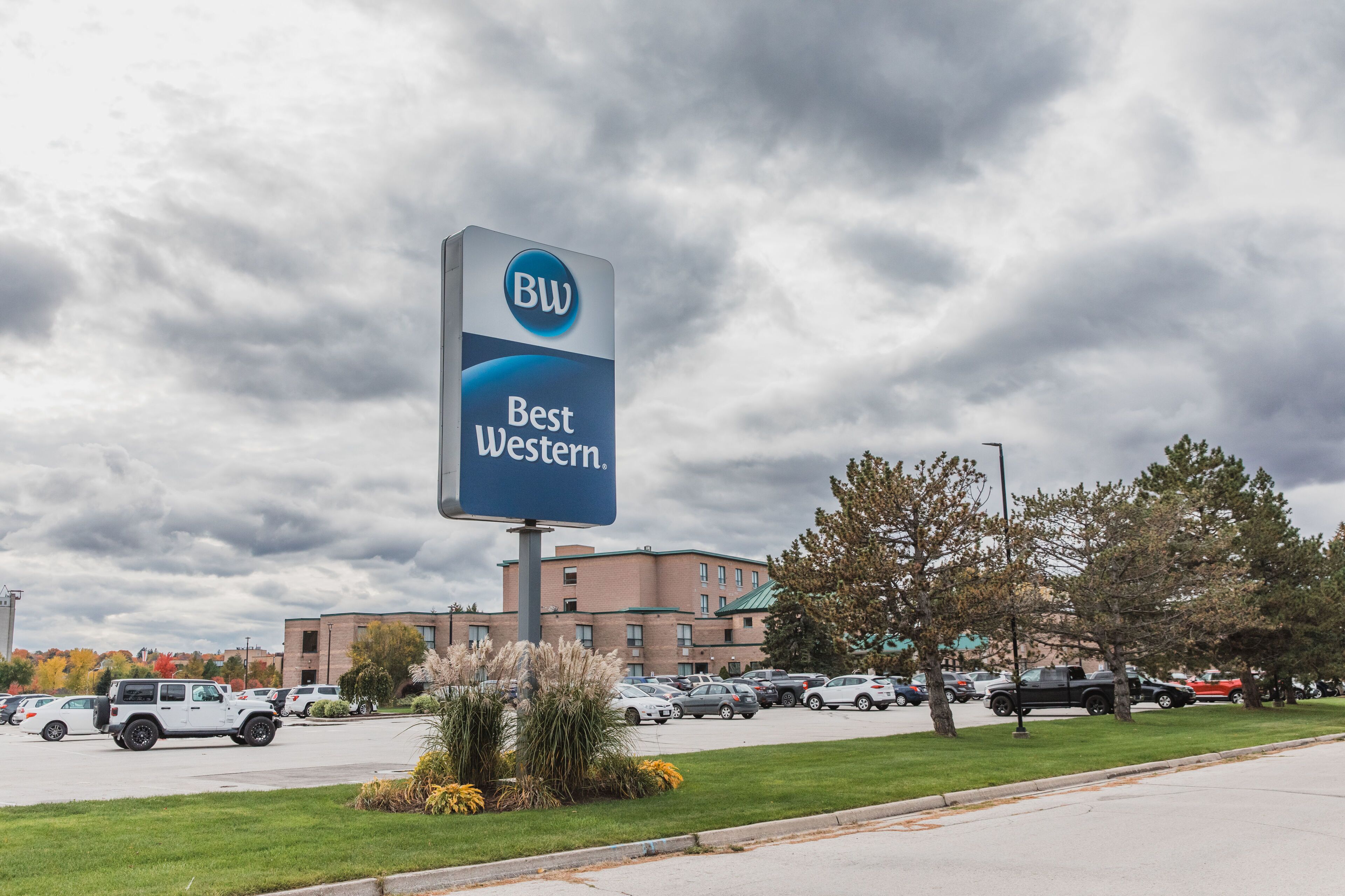 Señal de un hotel Best Western, con un estacionamiento y edificios al fondo.