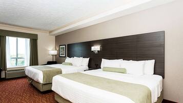 Una habitación de hotel con dos camas, un ventanal con cortinas, una lámpara de pared y un cuadro enmarcado.